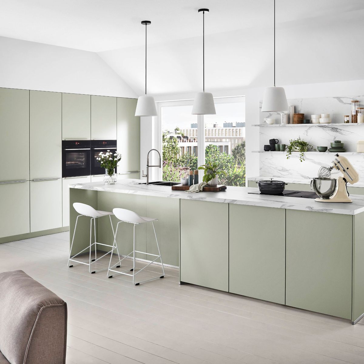 Sage green kitchen with marble-effect worktops and island seating designed by 21 Kitchens Ayrshire
