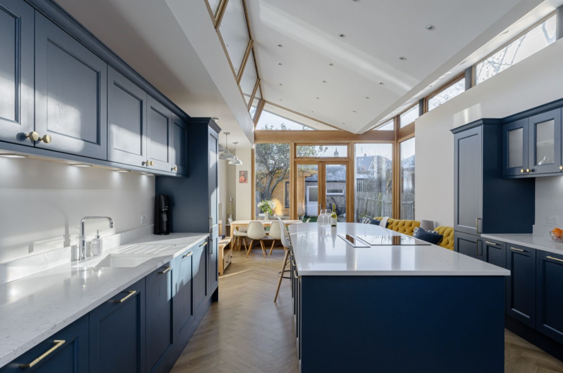 Blue fitted kitchen with large island, skylights and open-plan dining area by 21 Kitchens in Ayrshire.