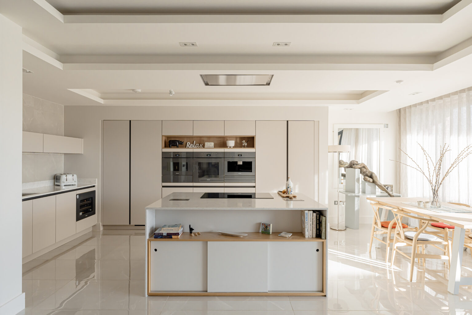Bright modern kitchen with island storage, integrated appliances and open-plan dining area by 21 Kitchens in Ayrshire.