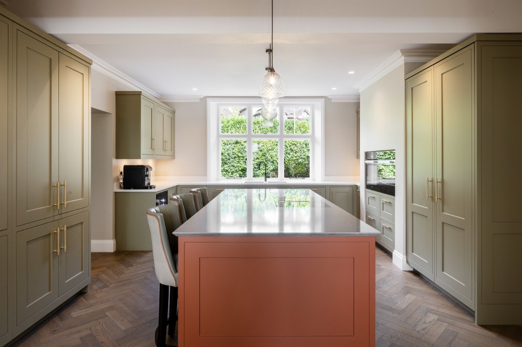 British painted shaker kitchen with sage green cabinets, terracotta island, brass handles and classic family layout by 21 Kitchens in Ayrshire.