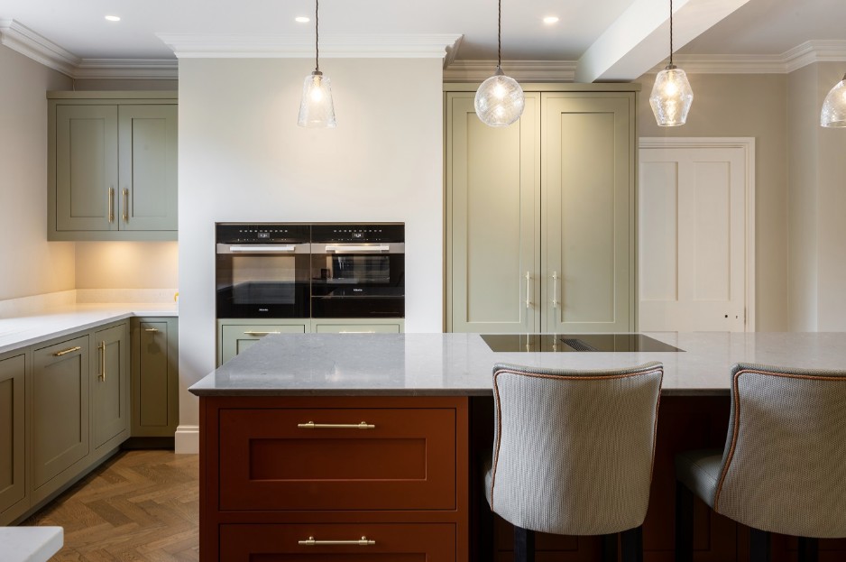British shaker kitchen with sage green cabinets, terracotta breakfast bar, brass handles and pendant lighting by 21 Kitchens in Ayrshire.