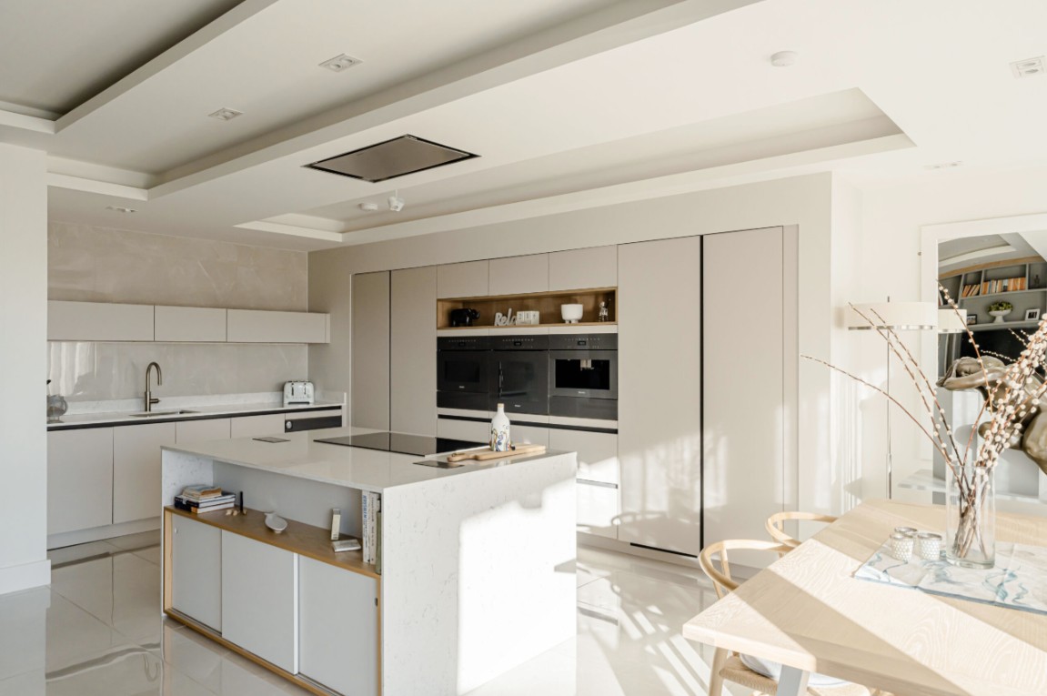 Cream modern kitchen with island, integrated appliances and bright dining space by 21 Kitchens in Ayrshire.