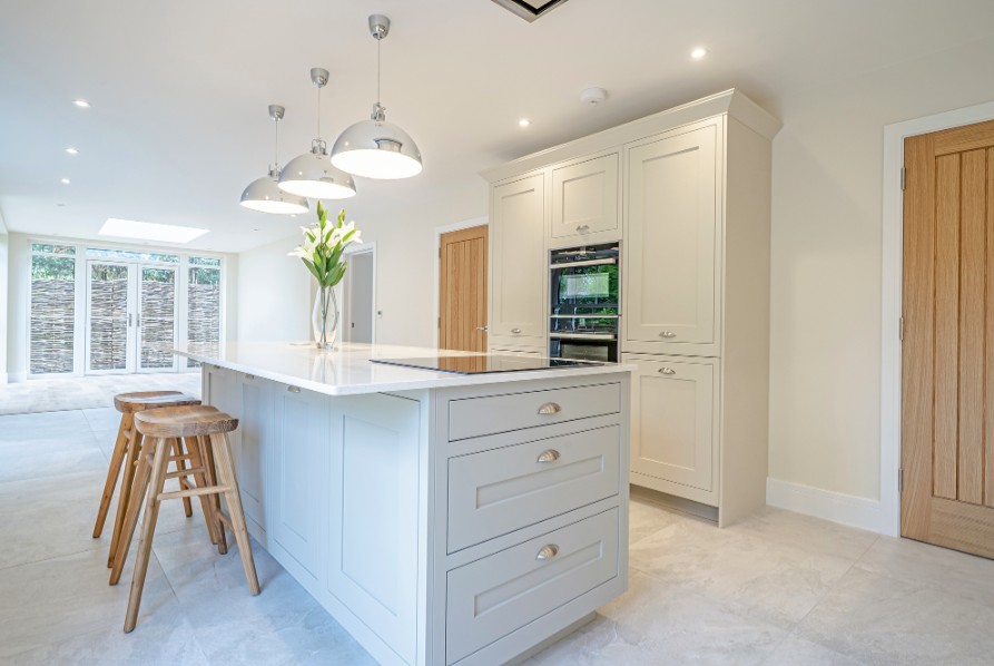 Cream shaker kitchen with island, pendant lights and wooden breakfast stools by 21 Kitchens in Ayrshire.