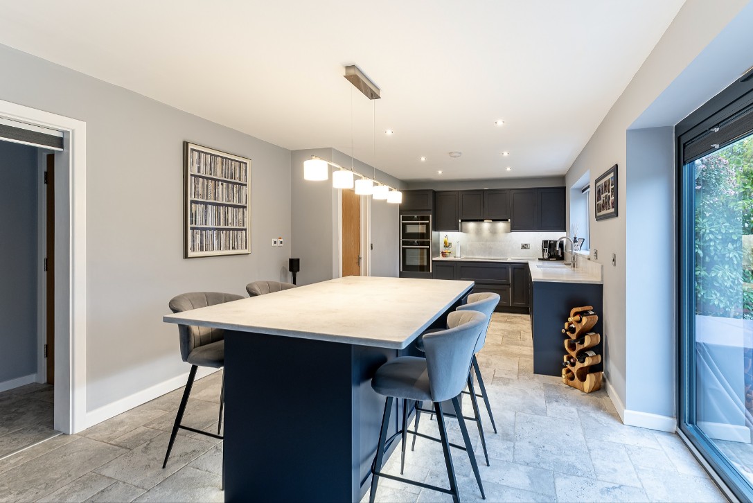 Grey German kitchen with large breakfast island, bar seating, integrated ovens and modern open-plan layout by 21 Kitchens in Ayrshire.