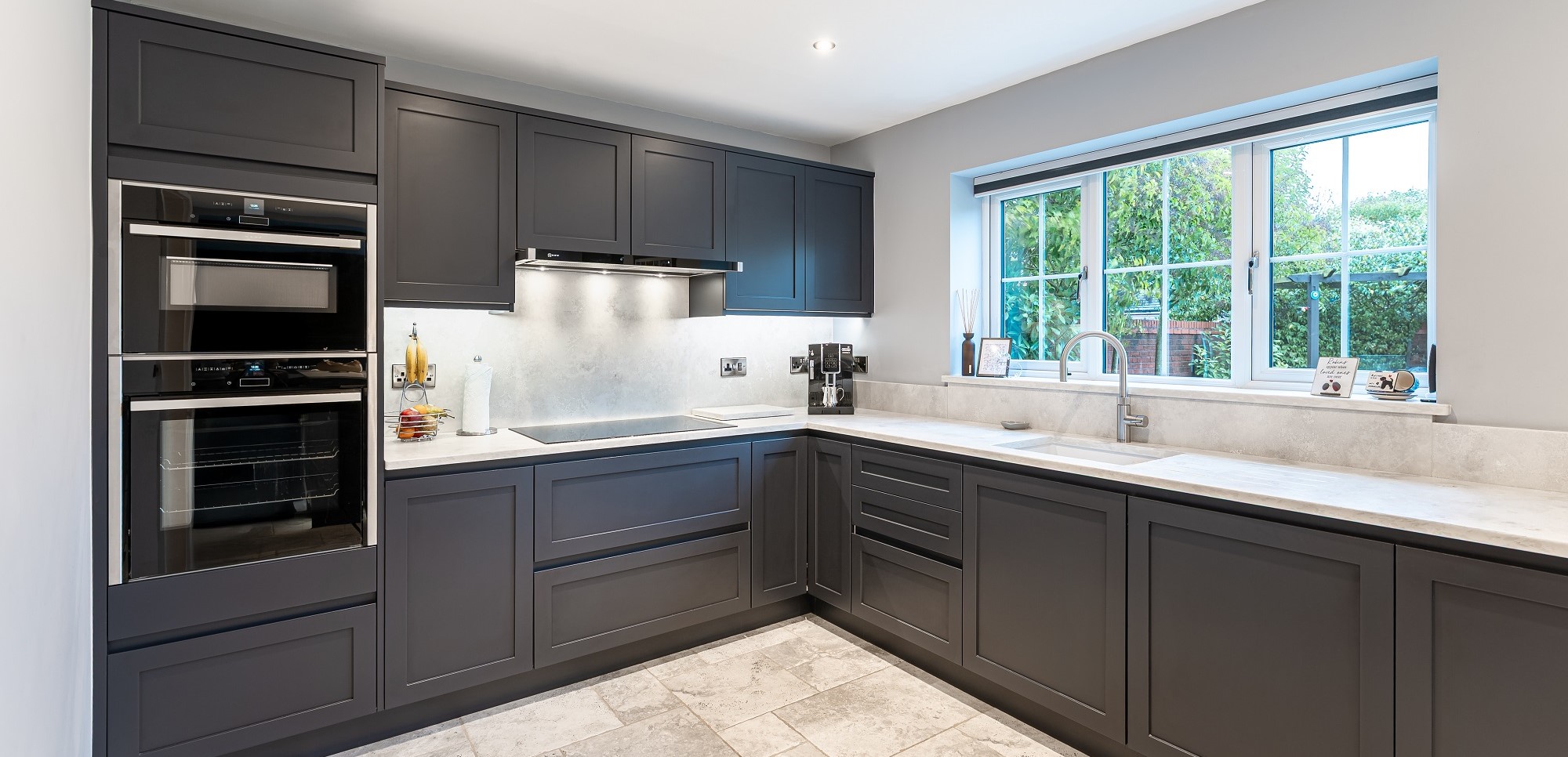 Grey shaker German kitchen with integrated ovens, light worktops and practical storage by 21 Kitchens in Ayrshire.