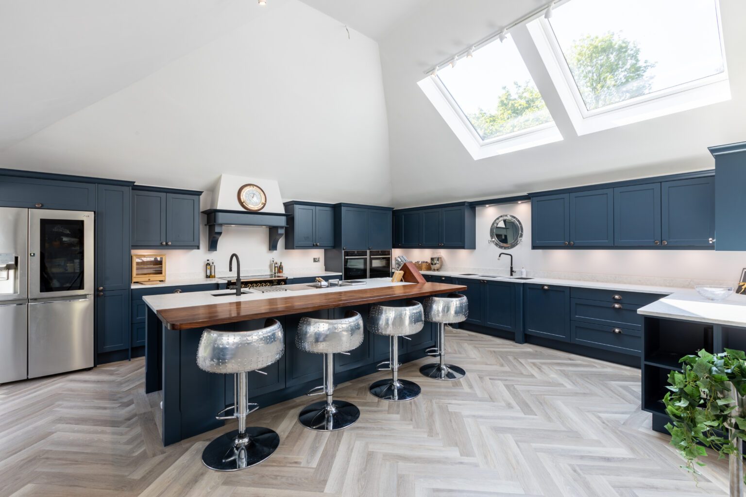 Luxury blue kitchen with large island, skylight windows, herringbone flooring and breakfast bar seating by 21 Kitchens in Ayrshire.