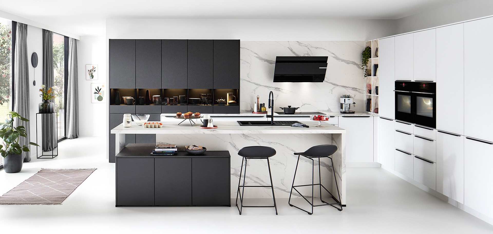 Modern white and black kitchen with marble-effect island and breakfast seating by 21 Kitchens Ayrshire.