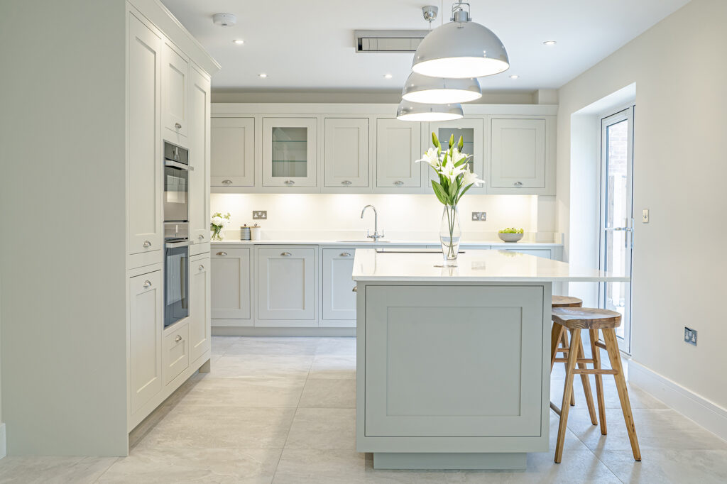 Neutral shaker kitchen with island, pendant lighting and breakfast seating by 21 Kitchens in Ayrshire.