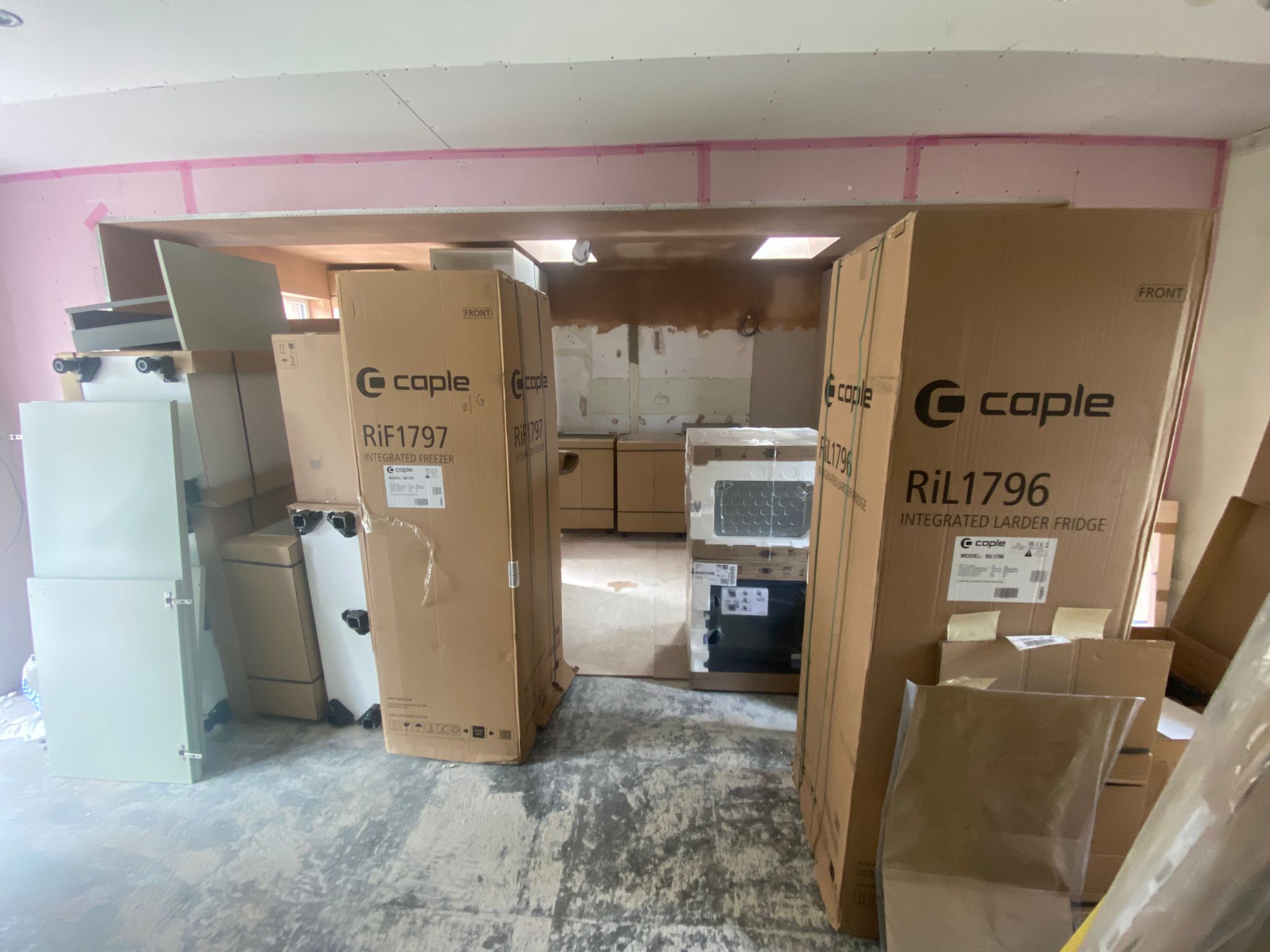 Kitchen renovation in progress with appliance delivery boxes and fitted units ready for installation.