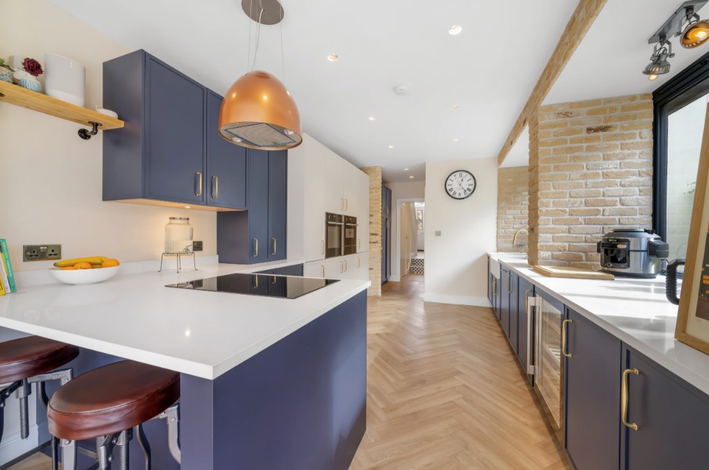 Open-plan Nobilia kitchen near Kilmarnock and Stewarton with navy cabinetry, quartz worktops and breakfast bar seating.